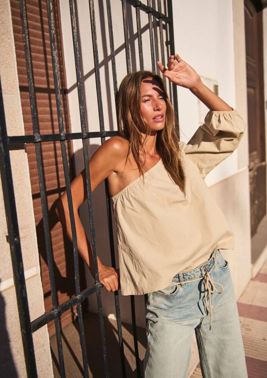 De Marloes one shoulder top beige kleur met losse pasvorm, pofmouw gecombineerd met lichte jeans.