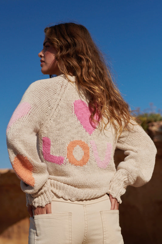 De gebreide ecru cardigan is gemaakt van 100% katoen met hartjes patroon van pastel tinten en gedetailleerde knopjes in hartvorm. Perfecte bohemian aanvulling voor je zomer garderobe.