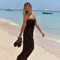 Ebony Maxi kleed zwart van Hot Lava op strand.  Hartvormige strapless jurk, bezet met schelpen en kraaltjes aan de buste.